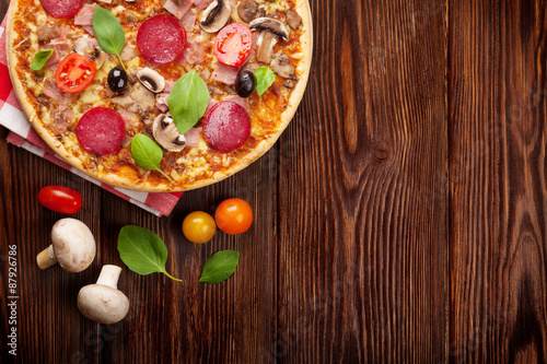 Italian pizza with pepperoni, tomatoes, olives and basil