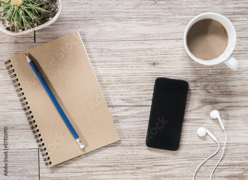 Smartphone  earphones  notebook and coffee on wooden background