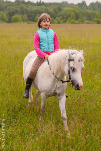 Little girl child walks on a white horse on the field Outdoors © andreipugach