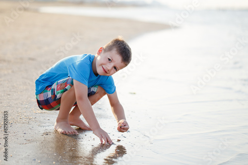 Little boy squat on beach photo