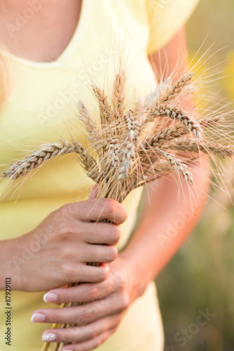 Girl with with ripe ears of barley in hand
