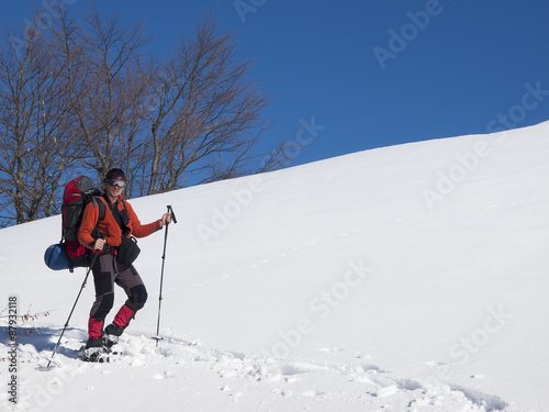 A man in snowshoes is in the mountains in the snow.