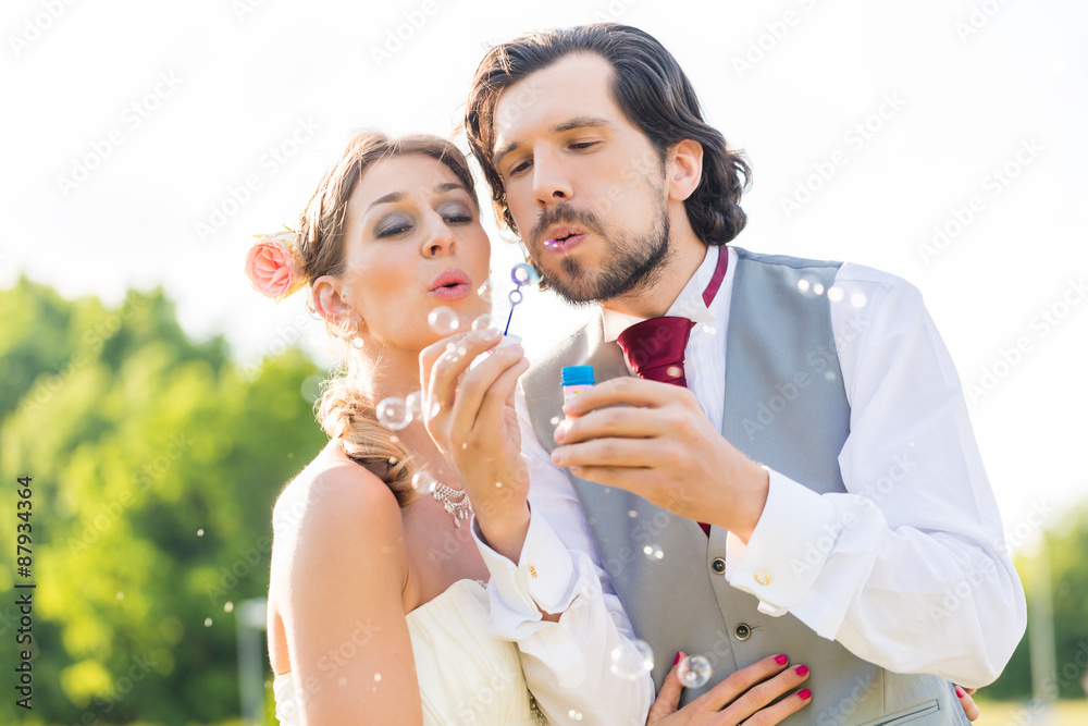 Wedding bride and groom blowing bubbles outside on field Wedding bride and groom blowing bubbles outside on field