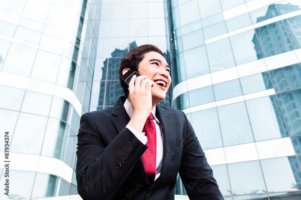 Asian business man talking outside to mobile phone Asian business man talking outside to mobile phone