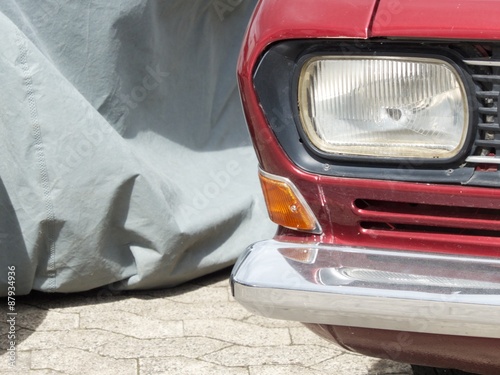 Scheinwerfer einer roten zweitürigen Limousine der  Sechziger Jahre im Sommer bei Sonnenschein beim Oldtimertreffen Golden Oldies in Wettenberg Krofdorf-Gleiberg bei Gießen in Hessen