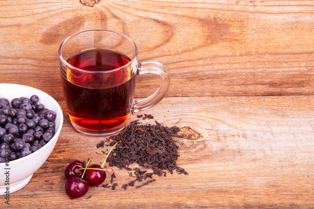 cup of tea, sweet cherry and blueberry in white bowl on a wooden cup of tea, sweet cherry and blueberry in white bowl on a wooden