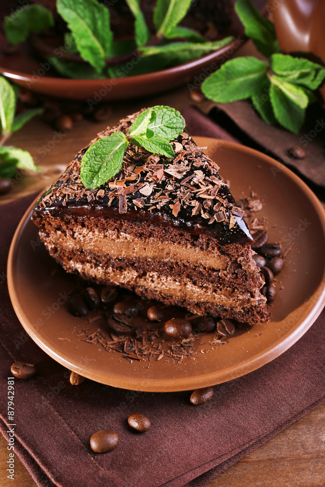Delicious chocolate cake with mint on plate on table close up Delicious chocolate cake with mint on plate on table close up