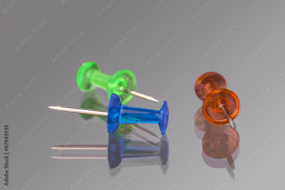 Pins on a reflective surface, red, blue and green pin Pins on a reflective surface, red, blue and green pin
