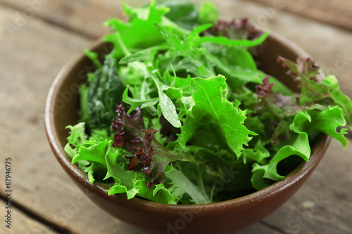 Fotografía Bowl of mixed green salad on wooden table, closeup