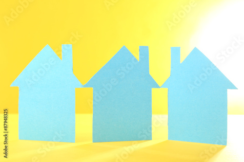 Color paper houses on yellow background