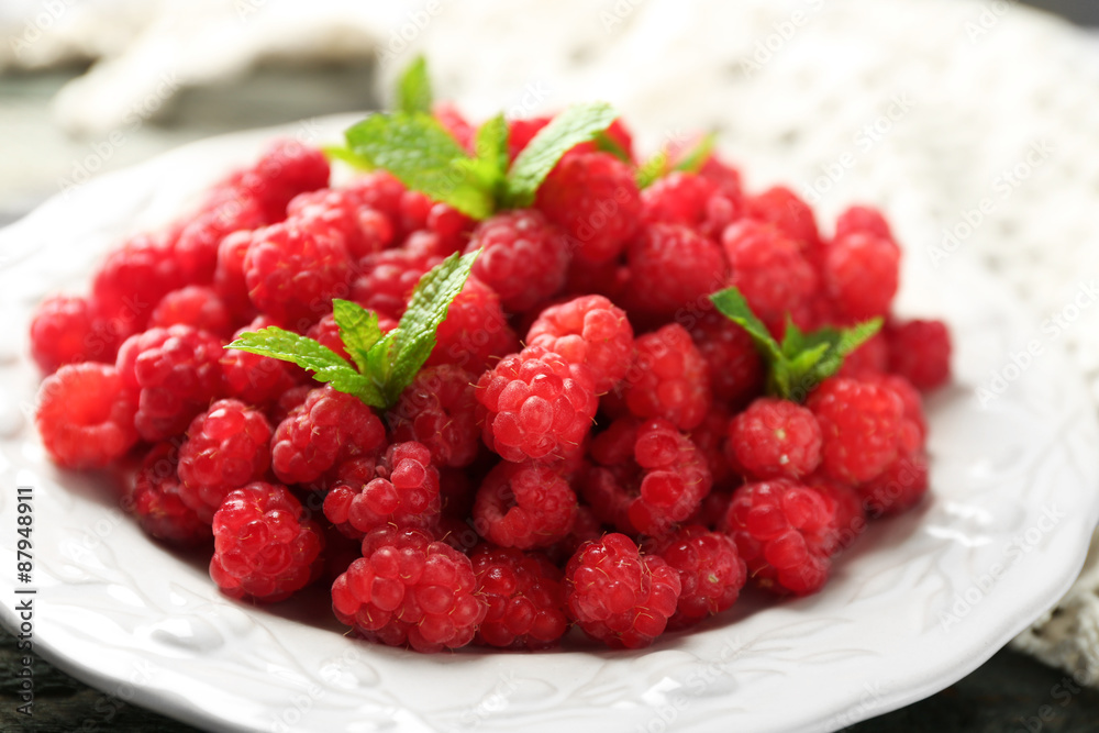 Sweet raspberries on plate on wooden background Sweet raspberries on plate on wooden background