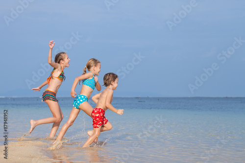 Three happy children playing on the beach