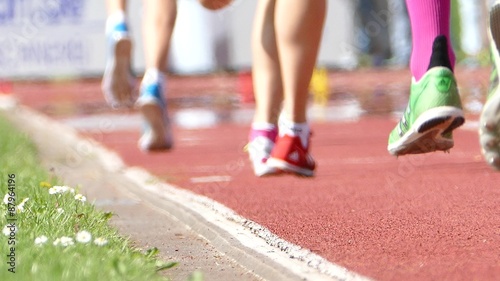 Runner group in a stadium. Low perspective with wafting hot air. Focus is on amount of the daisies at the side rim