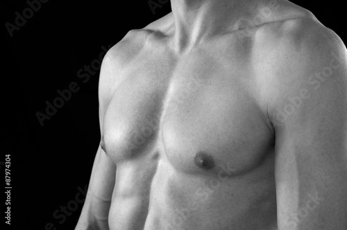 The upper chest of a lean but muscular young man. In black and white.