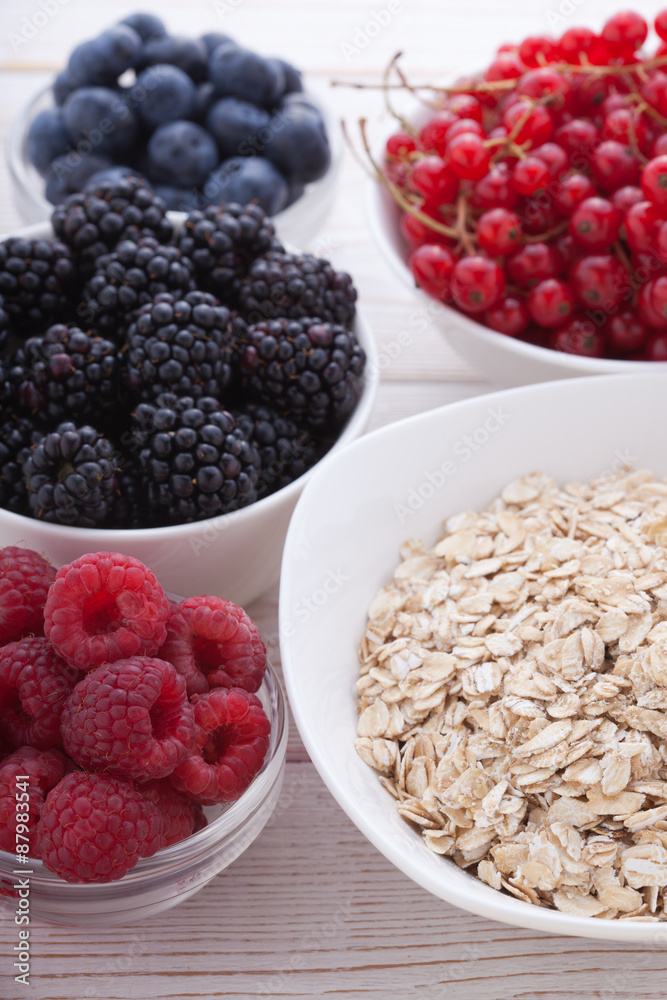Breakfast - berries, fruit and muesli on white wooden Breakfast - berries, fruit and muesli on white wooden