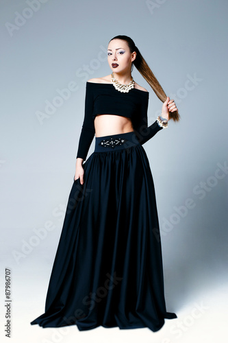 Beautiful female model posing in elegant black clothes in studio