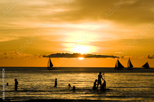 Sunset and sailing boats on white beach in Boracay Philippines
