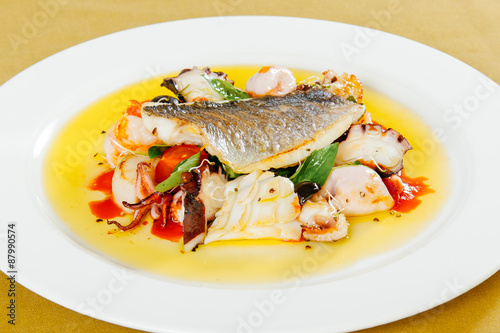 Dorado with seafood and cherry tomatoes on a white plate