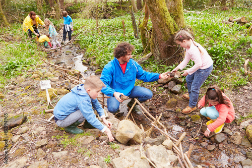 Children And Adults Carrying Out Conservation Work On Stream