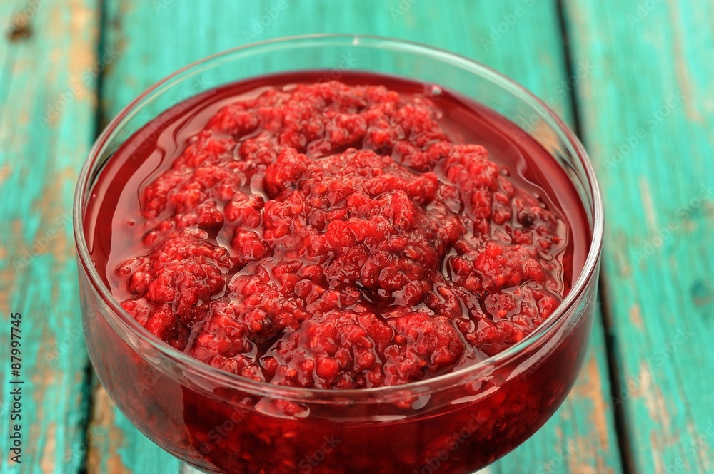 Fresh homemade raspberry jam in glass jar on old turquoise table Fresh homemade raspberry jam in glass jar on old turquoise table