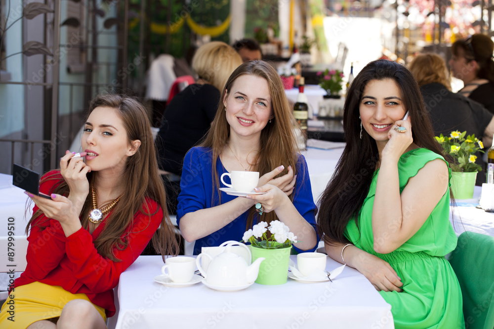 Three happy beautiful girls girlfriend drinking tea in a summer