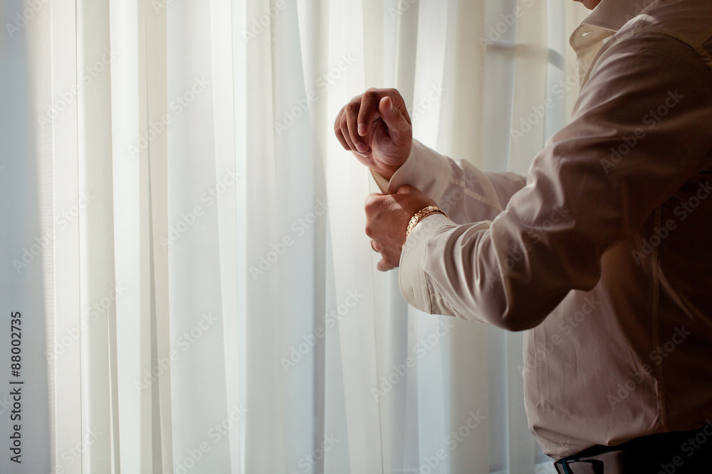 The man in the white shirt in the window wears a gold watch.