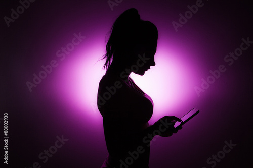 Silhouette of girls holding the phone in her hand.
