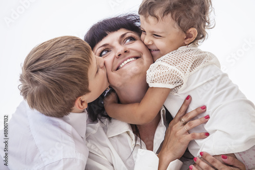 Woman smiling mother that kissing kids boy and girl