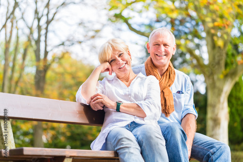 Älteres Paar sitzt auf Park Bank im Herbst © Kzenon