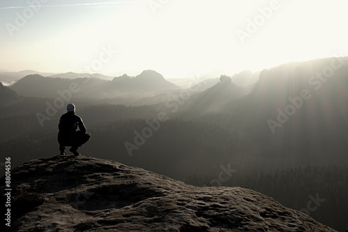 Hiker sits on a rocky peak and enjoy the mountains scenery