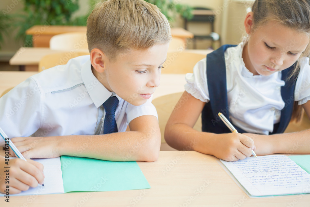 Students or classmates in school classroom sitting together at desk Students or classmates in school classroom sitting together at desk