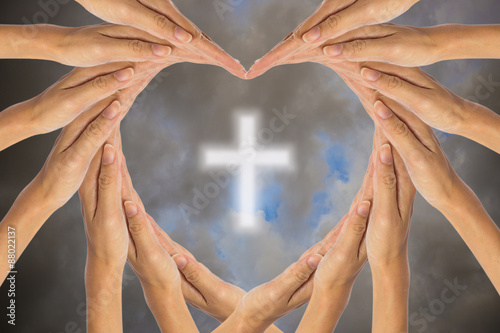 Hands make heart shape and Christian cross in the sky.
