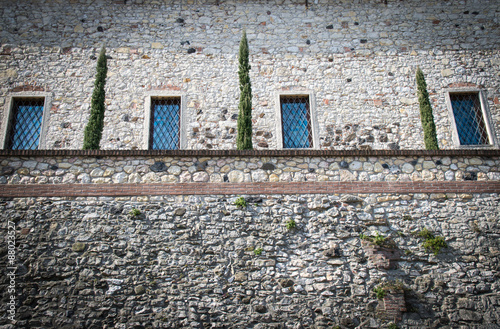 Stone wall of a medieval fortress with  windows and a small hang