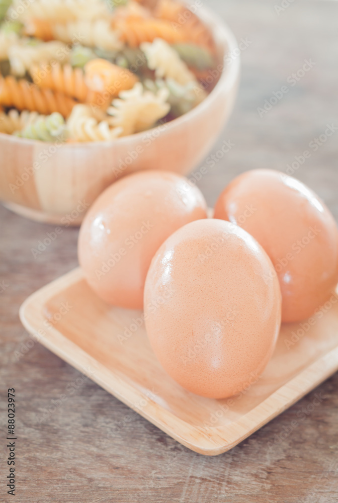 Fresh eggs on wooden plate with fusili Fresh eggs on wooden plate with fusili
