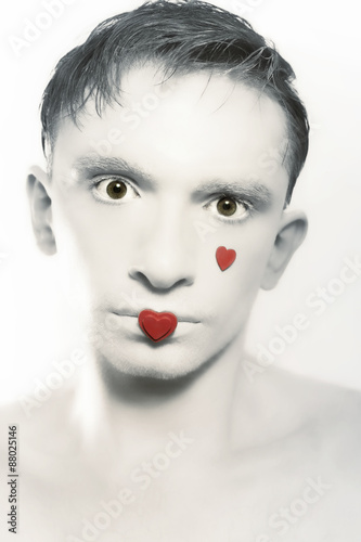 portrait of young brunette man with white skin and red heart on