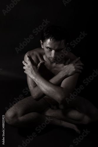 handsome young naked man sitting on the floor