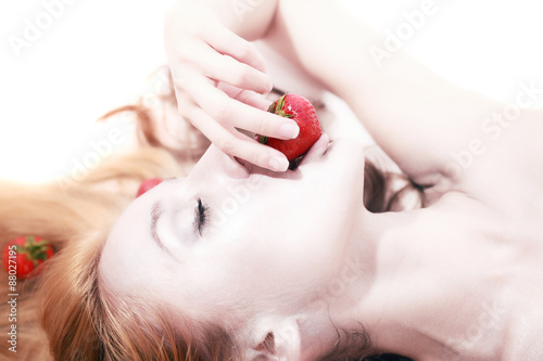 lyingl woman with silver makeup eating strawberries