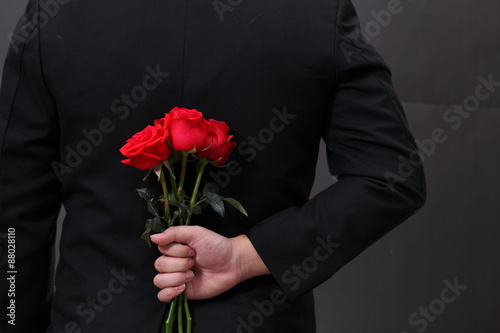 Man hiding a red rose flower behind his back. photo