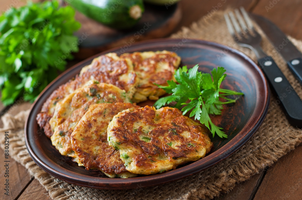 Zucchini pancakes with parsley on a wooden table. Zucchini pancakes with parsley on a wooden table.