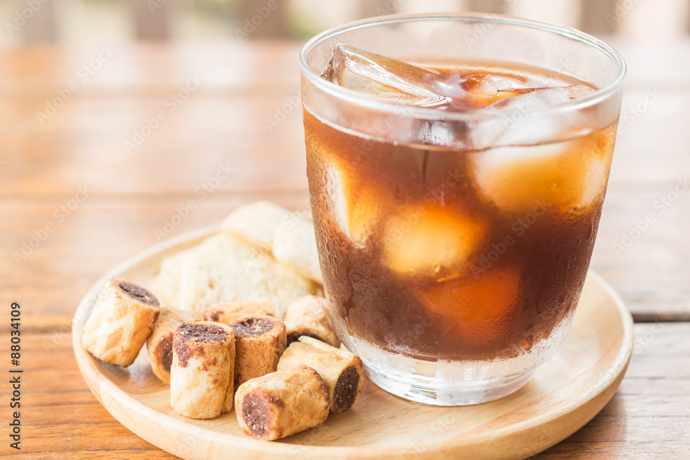 Glass of black iced coffee with some snack Glass of black iced coffee with some snack