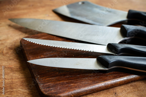 Set of kitchen knifes on wooden cutting board on old wooden tabl