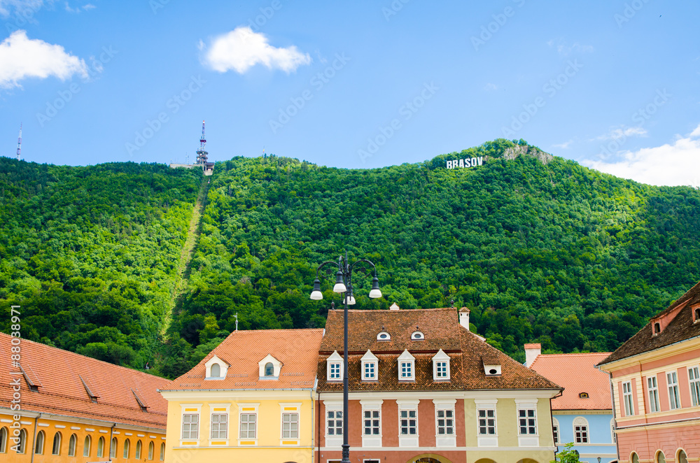 Brasov writing on the Tampa Hill with the fresh green forest and the cable route in the background and historic buildings on the foreground Brasov writing on the Tampa Hill with the fresh green forest and the cable route in the background and historic buildings on the foreground