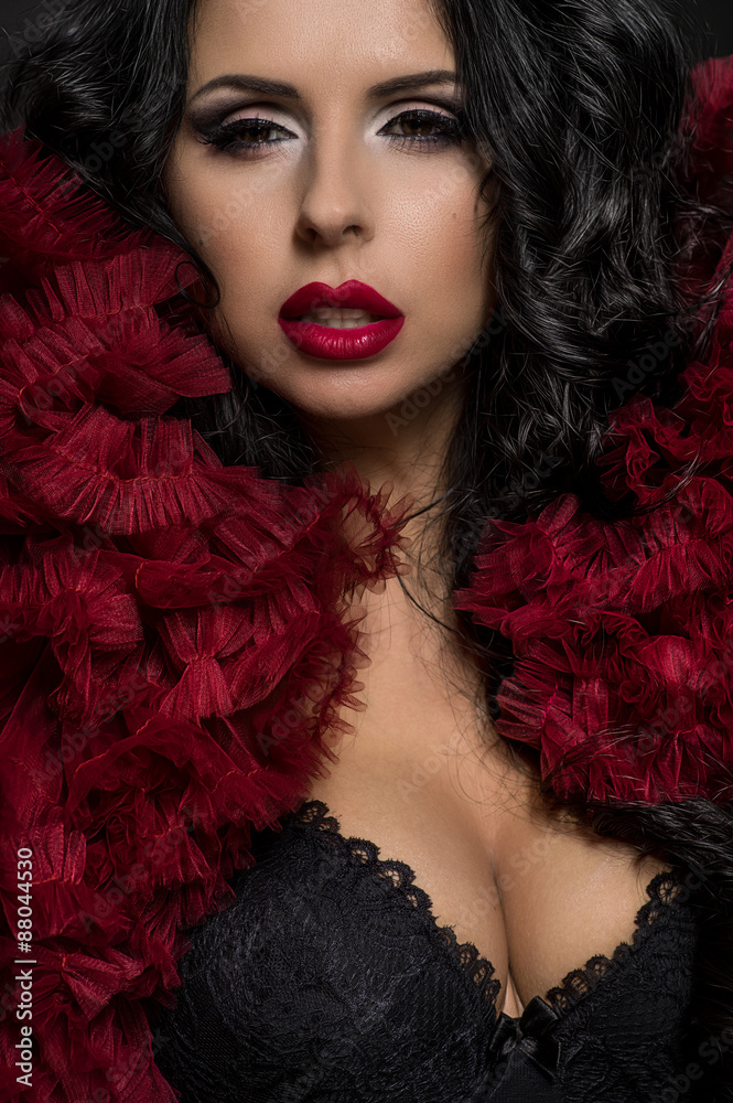 Sexy brunette woman in black underclothes and red fluffy bolero on dark background Sexy brunette woman in black underclothes and red fluffy bolero on dark background