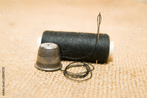 Needle, thimble and thread spool on the old cloth photo