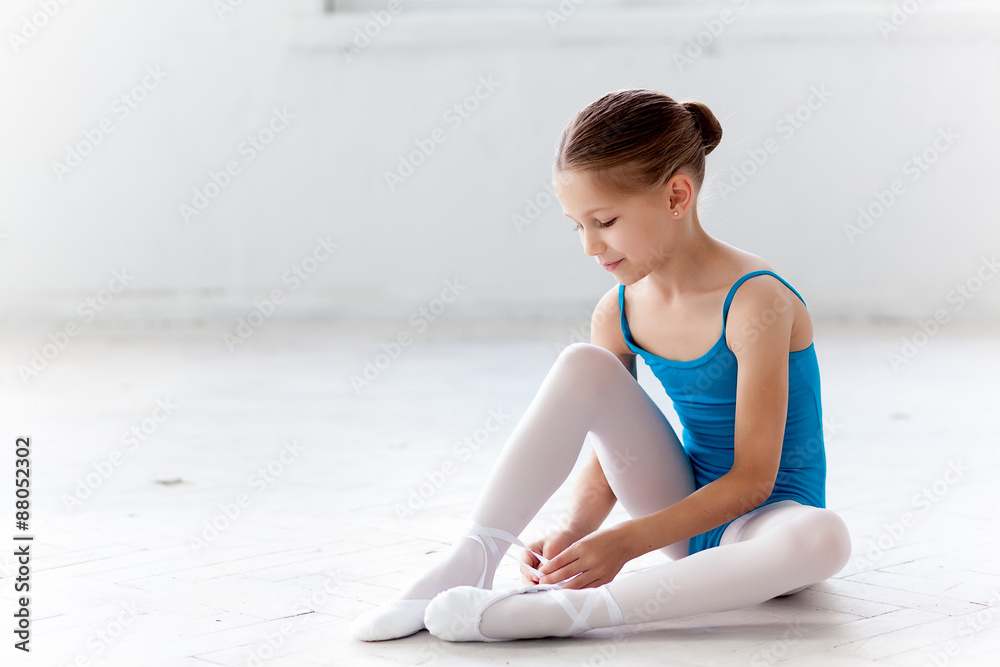 Fototapeta premium Beautiful little ballerina in blue dress for dancing puting on