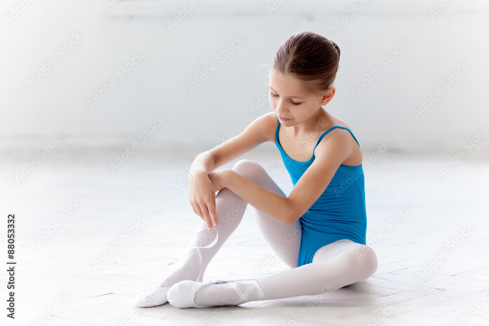 Fototapeta premium Beautiful little ballerina in blue dress for dancing puting on