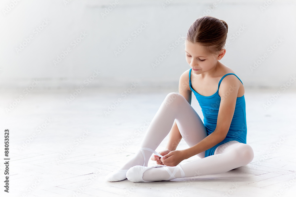 Fototapeta premium Beautiful little ballerina in blue dress for dancing puting on