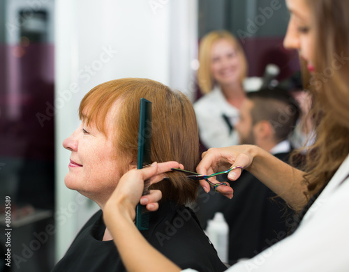 Woman cuts hair at the barbershop