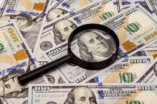 Hundred dollar banknote under magnifying glass