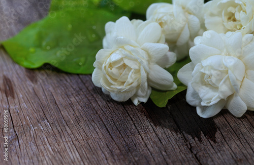 Jasmine flowers and leaves on brown wooden table.